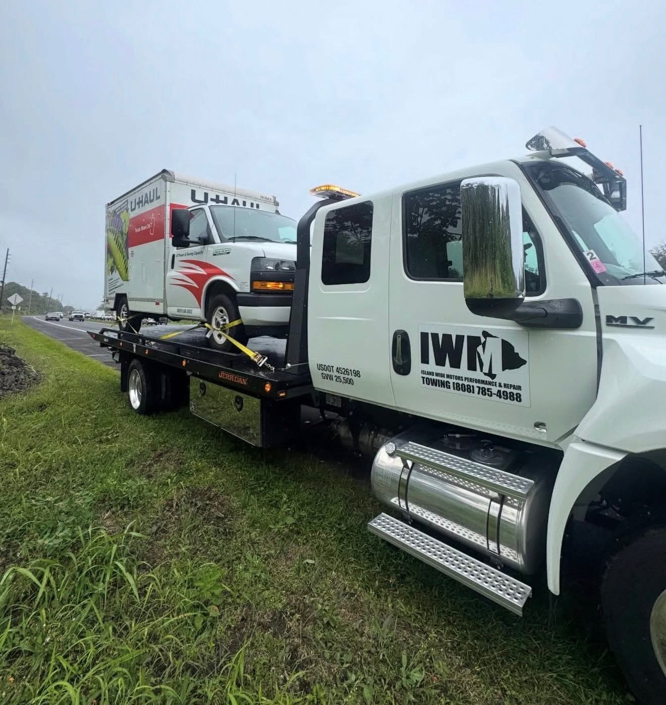 Island Wide Motors truck transporting a U-Haul
